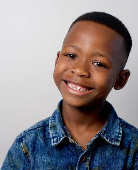 Cute African boy smiling head and shoulders Formal portrait with studio lighting Strand Cape Town South Africa